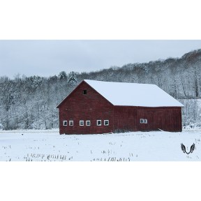 A red barn located in a snow covered field